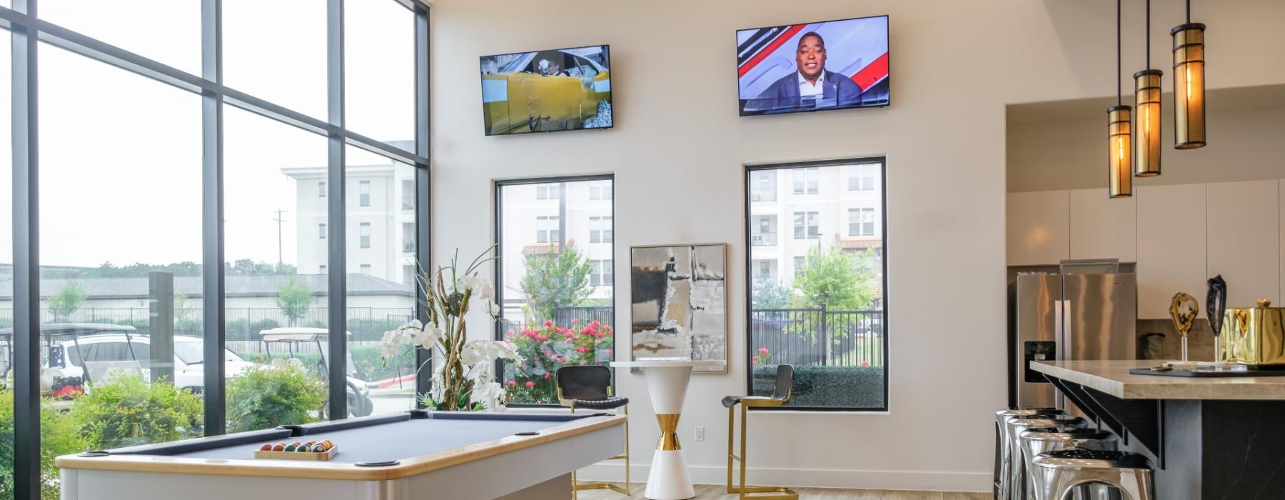 a room with a pool table tv chairs and a large window