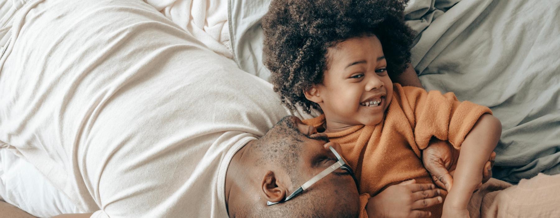a person and a child lying on a bed