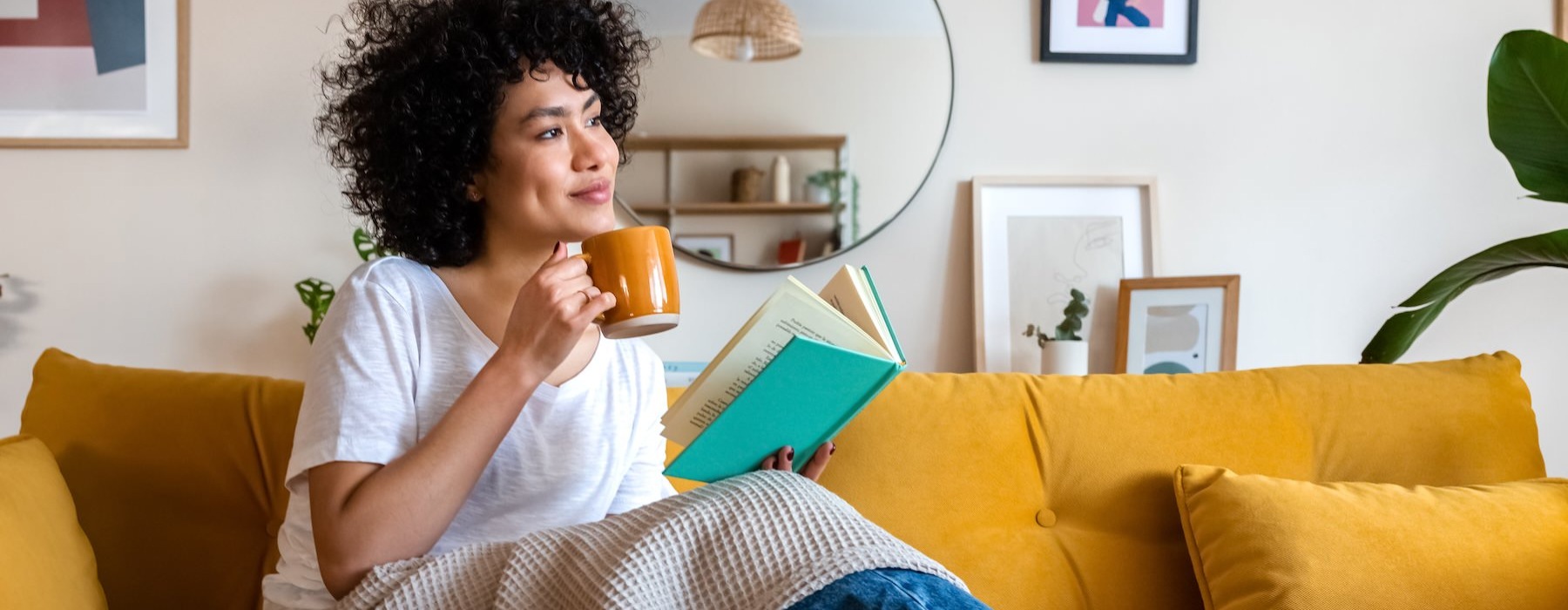 a woman drinking coffee on a yellow sofa