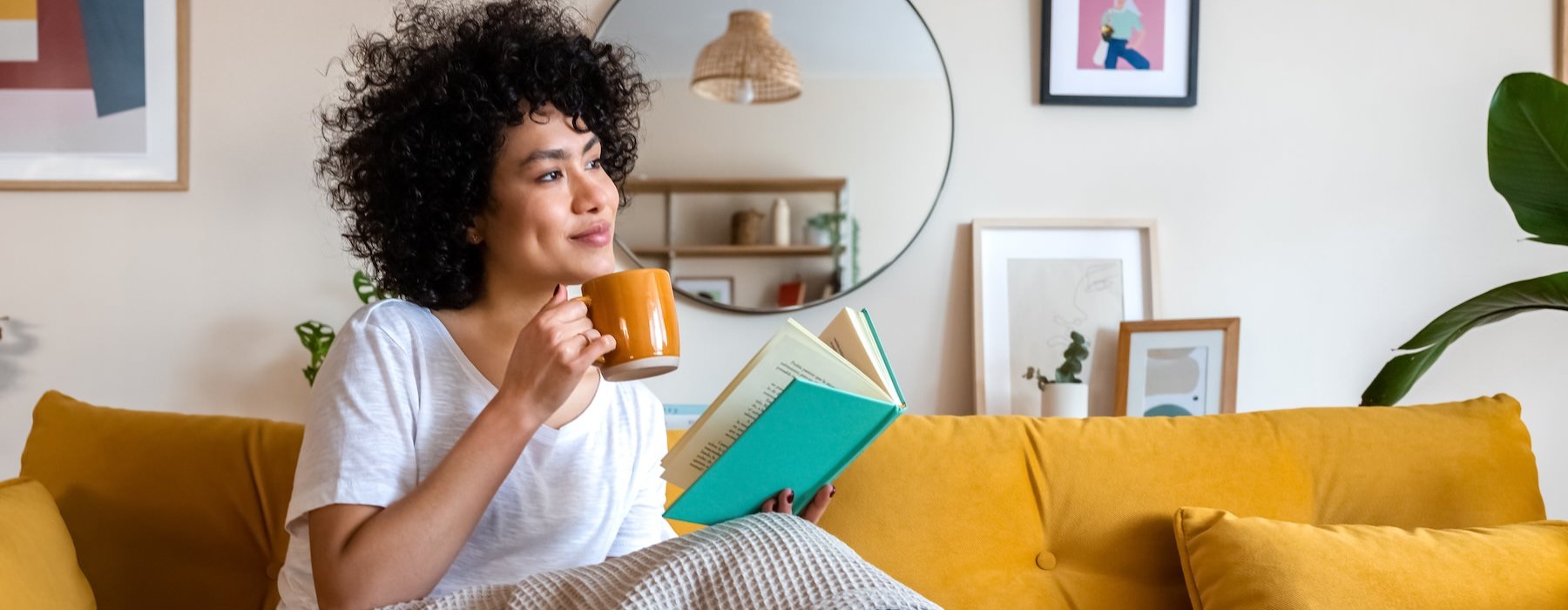 a woman drinking coffee on a yellow sofa