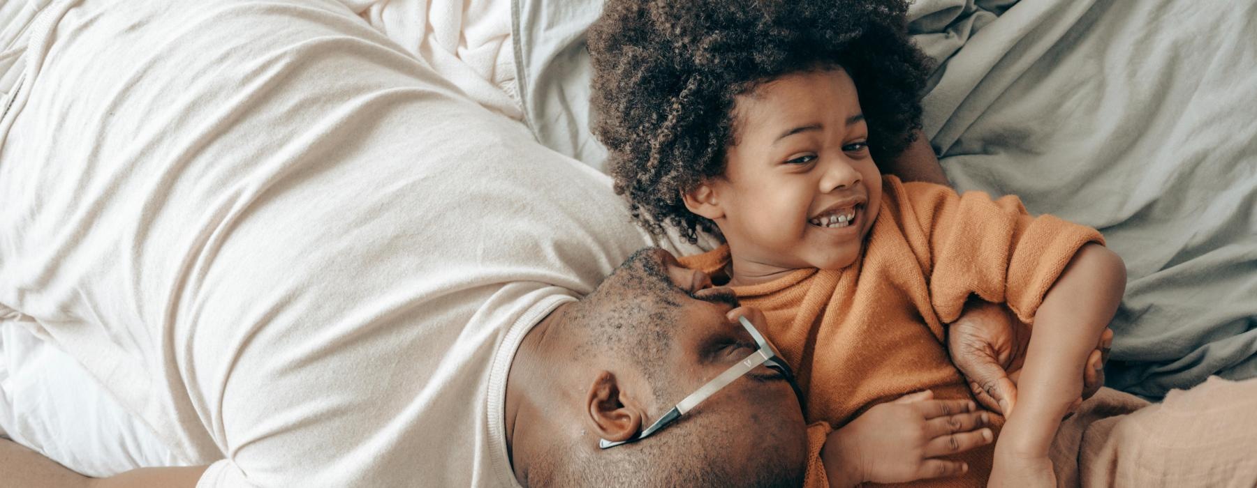 a person and a child lying on a bed