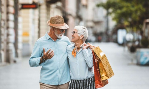 a man and woman holding shopping bags while walking